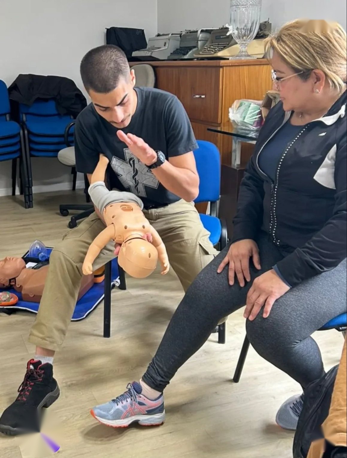 Fernando Wolff demonstrando manobra em um manequim de bebê, com uma aluna observando